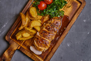 Chicken fillet in sweet and sour sauce with potatoes on a wooden board