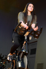 Fototapeta na wymiar Woman in gym spinning on fitness bike. High quality photo