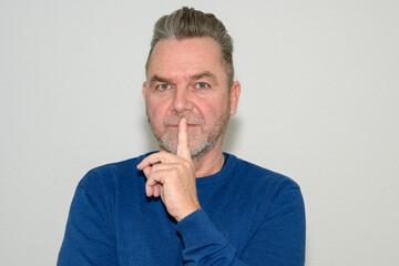Middle-aged man making a shushing gesture