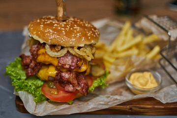  delicious burger with double cutlet and French fries on a wooden board