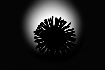 Silhouette of a virus on an illuminated black background. Template for the letter. Model of coronavirus or flu from cotton swabs. Black and white image. Blurred background.