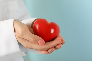 Female doctor hands holding red heart, close up