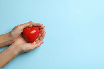 Female hands holding heart on blue background, space for text