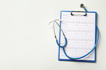 Stethoscope and clipboard with electrocardiogram on white background