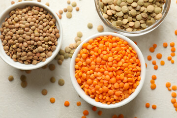 Bowls with different legumes on white textured background