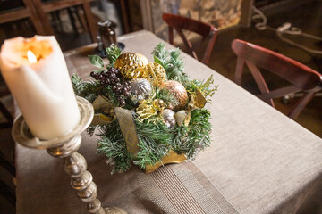 Christmas candle and decorations on table with copy space. Vintage decor, decorations in a basket, lanterns, garlands,spruce branches on a white table.Details Scandinavian living room for Christmas.