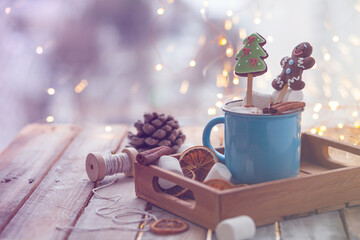 Delicious breakfast: hot chocolate with marshmallow and hand made gingerbread cookies. Rustic holiday decor, christmas lights on background, wooden table. Festive mood, cozy family atmosphere. Closeup