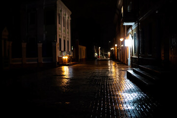 Night view of the city street with a brick road covered with ice, rain. Concept of an unsafe road for pedestr