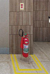A red Carbon Dioxide Fire Extinguisher on a metal stand in the foyer of a hotel, and marked out...