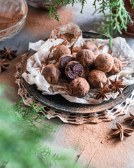 Chocolate truffles on black plate on wooden table, selective focus. Homemade chocolate candy truffles