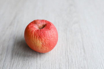 Red wrinkled apple isolated on the wooden table 