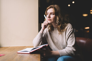 Young pensive woman with notebook in cafe