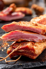 Dried pork ribs close-up on a dark table. Sliced jerky pork meat.