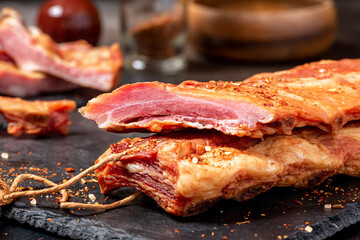 Dried pork ribs close-up on a dark table. Sliced jerky pork meat.