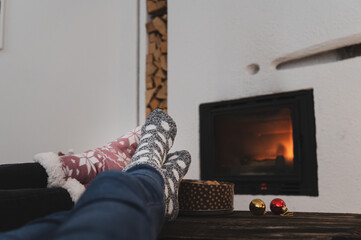   Feet of two girlfriends  on a rustic wooden table in front of a fireplace