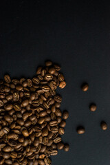 Obraz premium Close up of brown coffee beans in natural light on black table, black background in a dark theme. Moody picture with shadows. Sun rays.