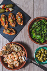 top view several plates and casseroles with traditional spanish tapas food served on a wooden table