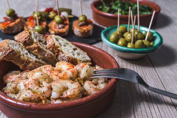 close-up view of a casserole with fried prawns with garlic and parsley and other tapas dishes