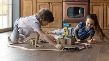 Choo-choo. Two happy little kids sister brother moving toy train by railroad of wooden block set....