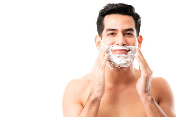 Young man putting shaving foam on face