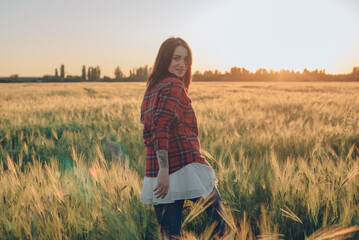 Naklejka na ściany i meble portrait of young female having fun and enjoying sunset in wheat field 