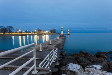 Concrete pier leading to boat entrance to lake Michigan with park in background with cloudy sky
