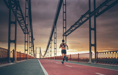 sporty female running outdoors on the bridge during sunrise