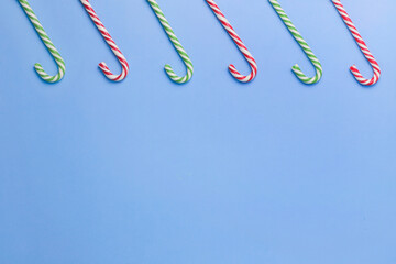 Five striped candy sticks lined up on a blue background. Christmas, New Year, holiday. Flat lay minimalism holiday concept. Copy space. 