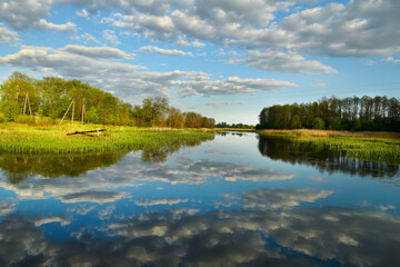 The lake and clouds are reflected in the water in spring at times. fresh spring foliage.