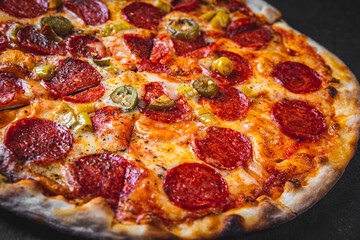 Pepperoni Pizza with Mozzarella cheese, salami, Tomato sauce, pepper, Spices. Italian pizza on Dark grey black slate background