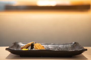 A grilled foie gras sushi on black plate