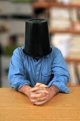 Homme à son bureau avec un seau en plastique sur la tête