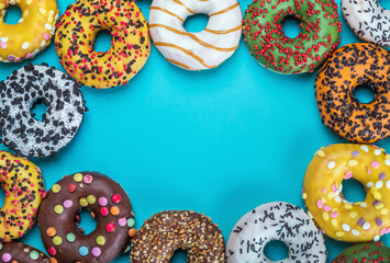 assortment of donuts with icing and different fillings on a blue background. place for your text