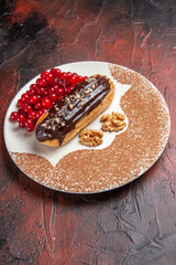 front view yummy choco eclairs with red berries on a dark background pie dessert cake sweet