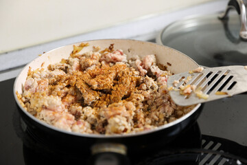young housewife fry meat in a pan and electric stove. Cooking dinner at home.
