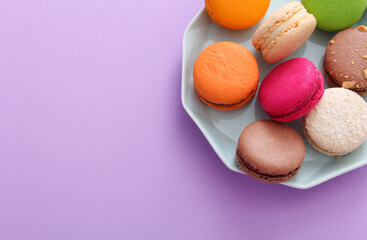 Close up of colorful french macaroons on blue plate on purple background. Almond cookies.Valentine's day sweet gift concept,holiday, celebration.