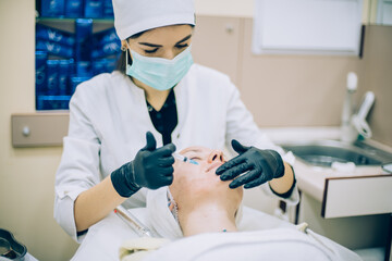young woman with problem skin receiving mesotherapy facial treatment in beauty clinic