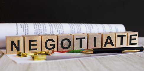 The word NEGOTIATE is written on wooden cubes near the pen and document.
