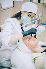 young woman with problem skin receiving mesotherapy facial treatment in beauty clinic