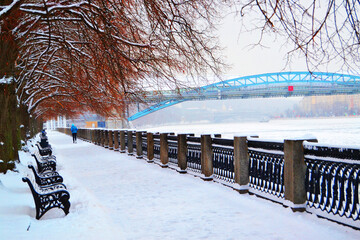 Park in winter in white snow near the bridge and benches