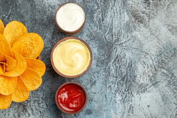 Half shot of homemade potato chips decorated like flower shaped and salt with ketchup mayonnaise on gray background