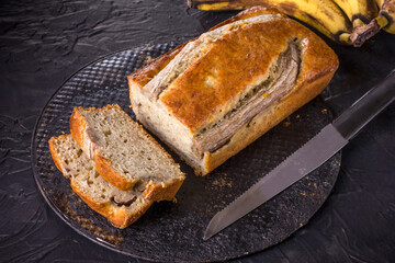 A traditional American dish is gluten and dairy free banana bread on a black concrete background. Top view, copy space.