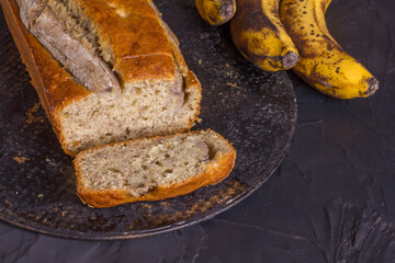 A traditional American dish is gluten and dairy free banana bread on a black concrete background. Top view, copy space.