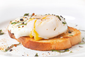 poached egg on toast with streaks of yolk on a white plate