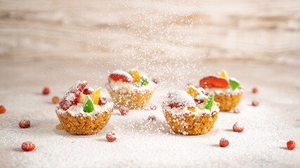 Sprinkling icing sugar over healthy cupcakes with cottage cheese, strawberries, banana, dried fruits. Winter background