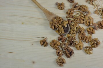 spoon with dried walnuts on a wooden table with copy space