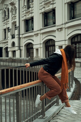 The girl stands at the fence on the bridge in the city. Fun in the city, a walk.