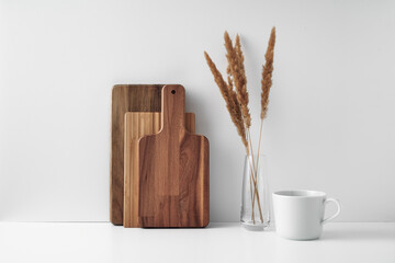 A mug, a transparent vase, and a wooden cutting board. Eco-friendly materials in the decor of the room, minimalism. Copy space, mock up.