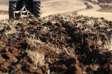 Tractor plows a field. Agricultural work in processing, cultivation of land. Farmers preparing land and fertilizing. Agricultural workers with tractors