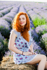 Summer portrait of a beautiful girl with long curly red hair. European girl in lavender field. Wavy Red Hair
